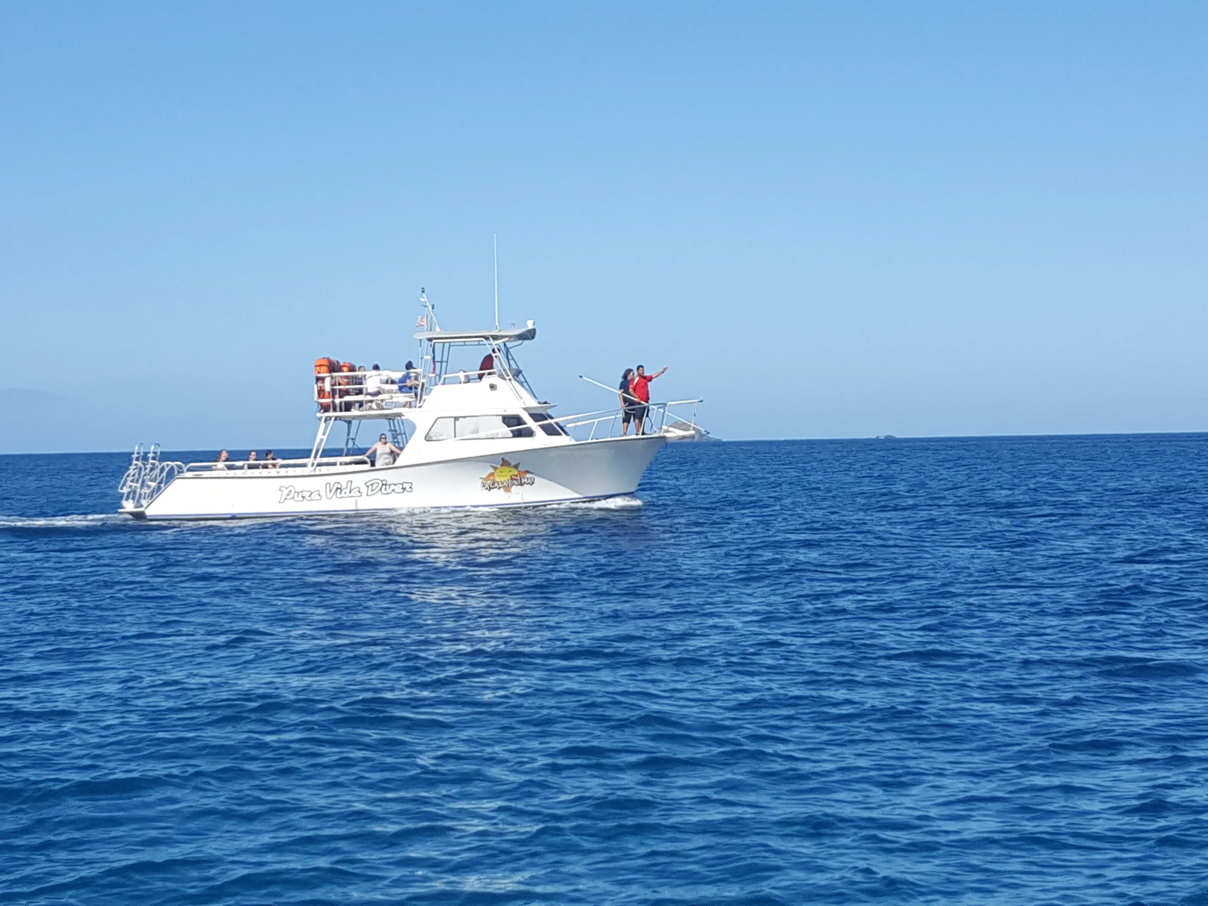 Pura Vida Diver from a distance on the ocean with two people peering out