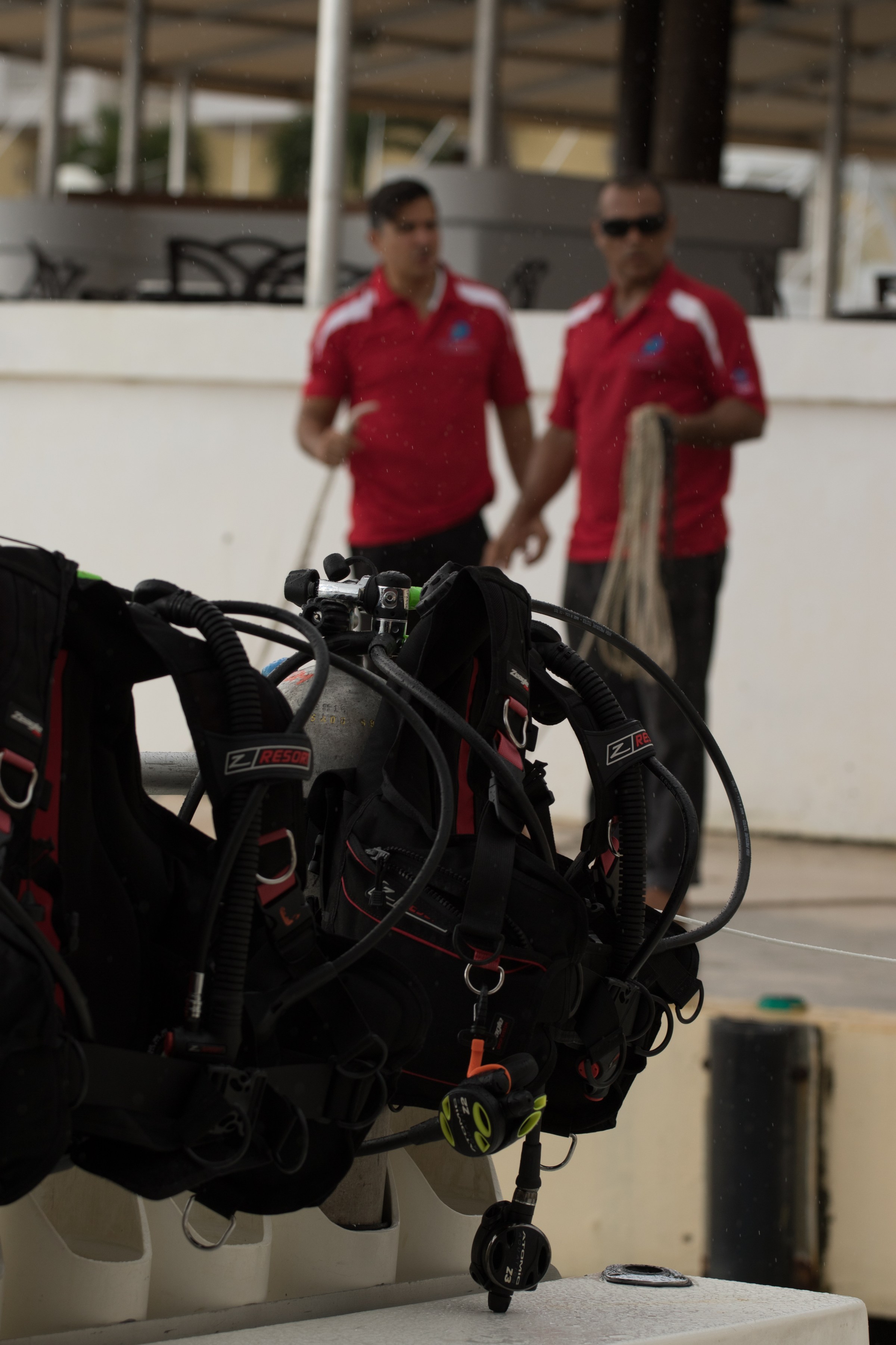 Scuba diving equipment at the diving center with two employees in the background